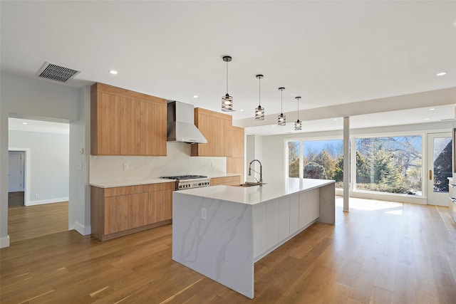 kitchen featuring a spacious island, visible vents, wall chimney exhaust hood, modern cabinets, and decorative light fixtures