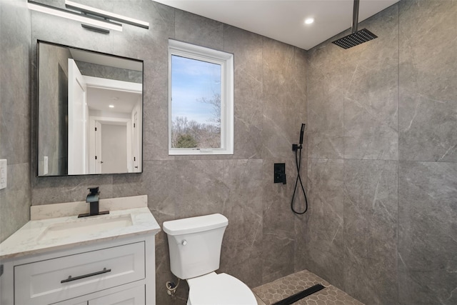 full bath with toilet, a walk in shower, tile walls, and vanity