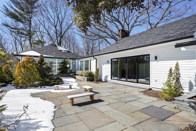 back of property with roof with shingles, a chimney, and a patio