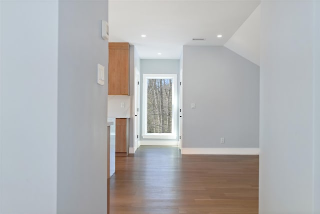 corridor featuring visible vents, wood finished floors, baseboards, lofted ceiling, and recessed lighting