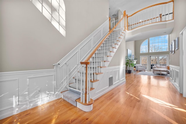 stairway with a towering ceiling, french doors, and hardwood / wood-style floors