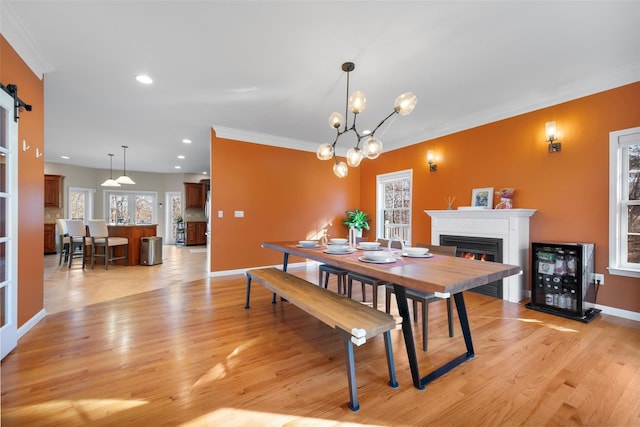 dining area featuring a notable chandelier, light hardwood / wood-style flooring, a barn door, and crown molding