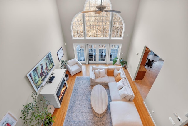 living room featuring a high ceiling, ceiling fan, and hardwood / wood-style flooring