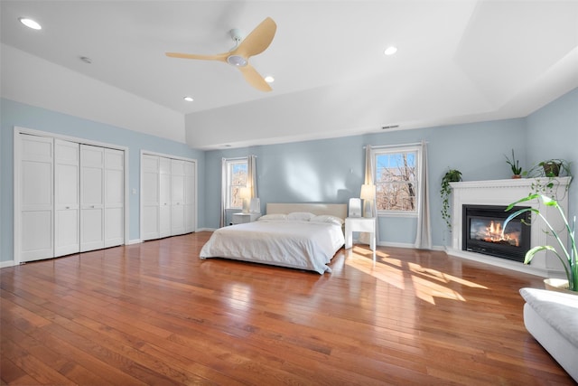 bedroom with a raised ceiling, ceiling fan, and wood-type flooring