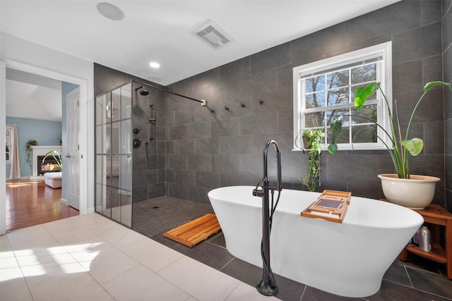 bathroom with tile walls, shower with separate bathtub, and tile patterned floors