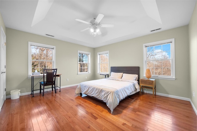 bedroom featuring ceiling fan, hardwood / wood-style floors, and a raised ceiling