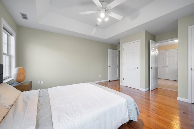 bedroom with a raised ceiling, ceiling fan, and hardwood / wood-style floors