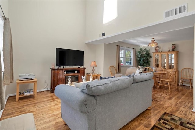 living room featuring a towering ceiling and light hardwood / wood-style flooring