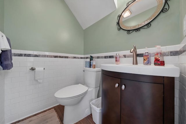 bathroom featuring vanity, vaulted ceiling, tile walls, hardwood / wood-style floors, and toilet