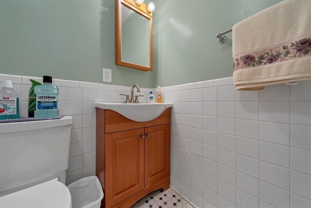 bathroom featuring vanity, toilet, and tile walls