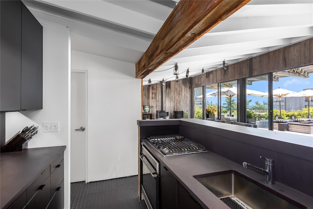 kitchen with vaulted ceiling with beams, dark brown cabinetry, sink, and appliances with stainless steel finishes