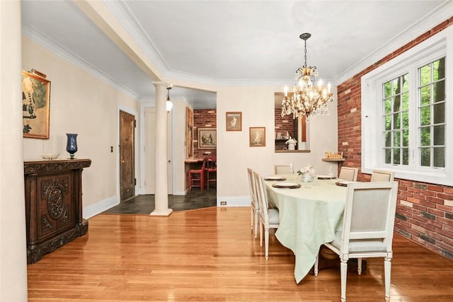 dining room with decorative columns, a notable chandelier, ornamental molding, and brick wall