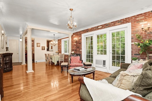 living room with decorative columns, crown molding, and brick wall