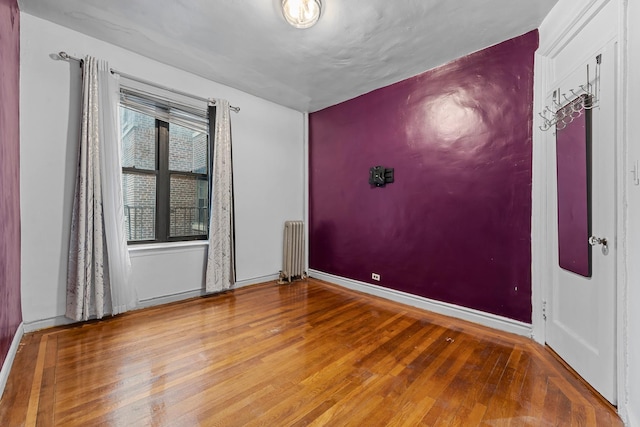 unfurnished room featuring hardwood / wood-style floors and radiator