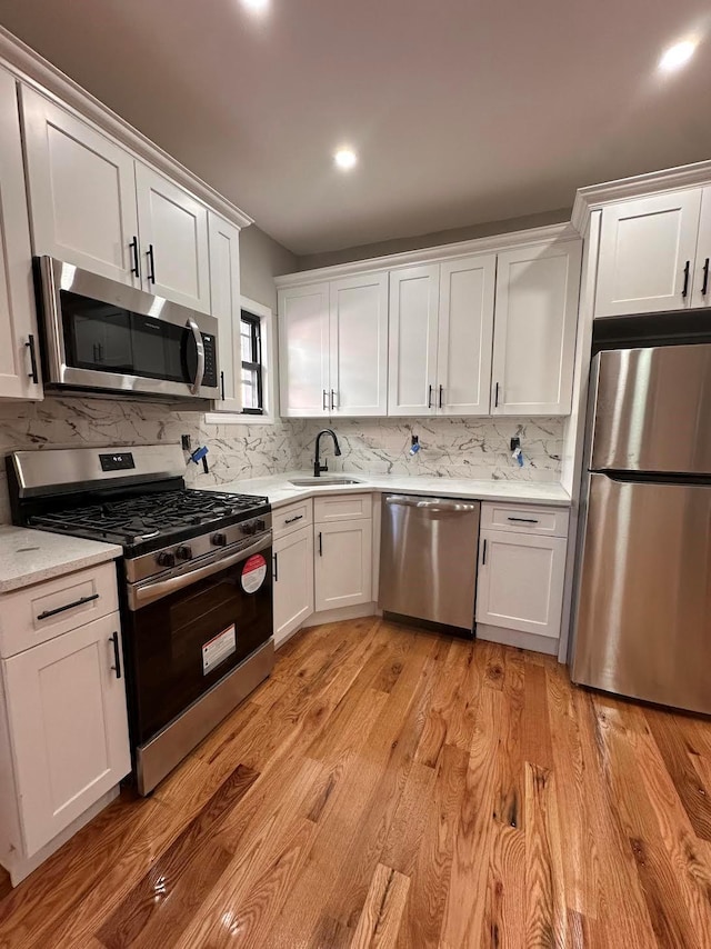 kitchen featuring tasteful backsplash, sink, white cabinets, and stainless steel appliances