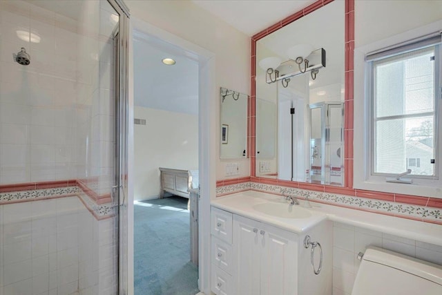 bathroom featuring vanity, toilet, a shower with shower door, and a wealth of natural light