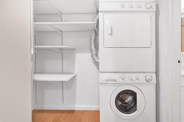 laundry room with stacked washer and clothes dryer and light hardwood / wood-style floors