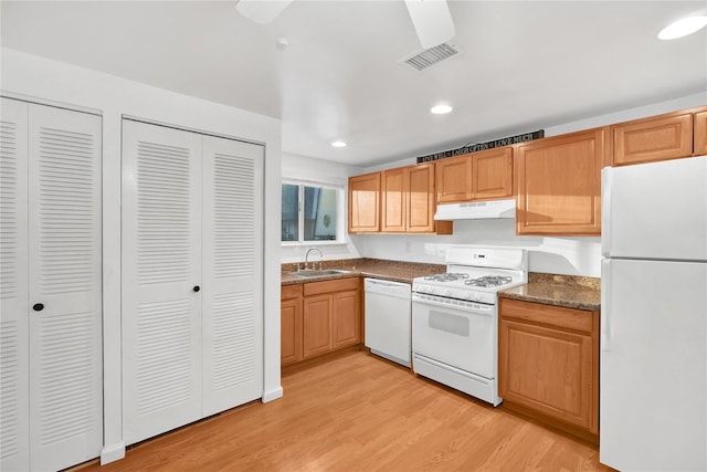 kitchen featuring white appliances, sink, light hardwood / wood-style flooring, and dark stone countertops