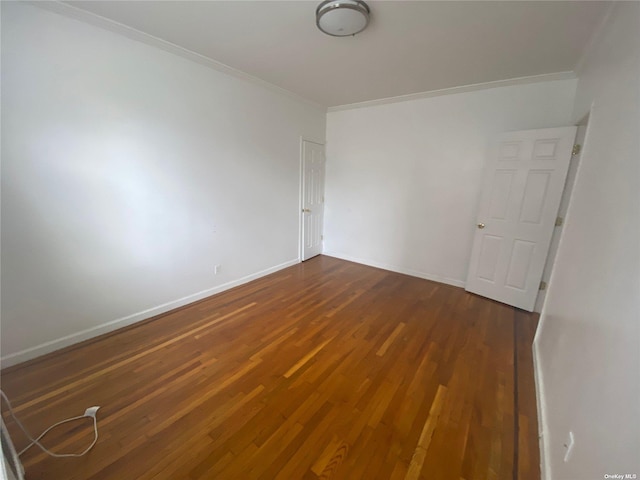 empty room featuring dark hardwood / wood-style flooring and crown molding