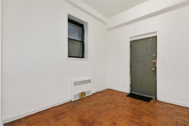 spare room featuring parquet flooring and radiator heating unit