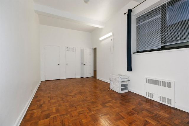 spare room with dark parquet flooring and radiator heating unit