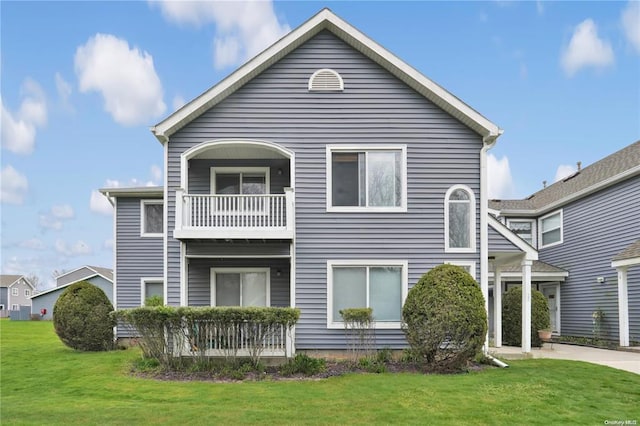 rear view of property with a yard and a balcony