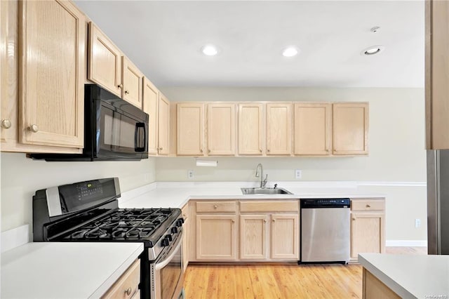 kitchen with stainless steel appliances, light brown cabinets, a sink, and light wood-style flooring