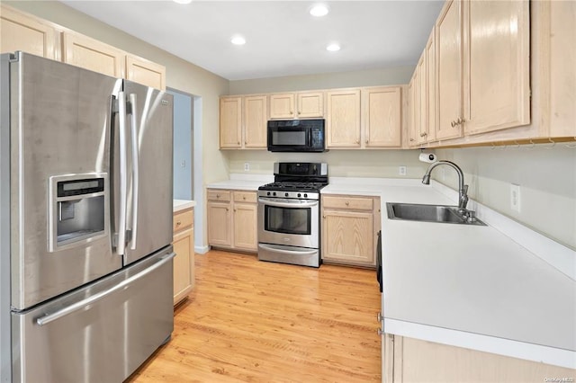 kitchen with light wood finished floors, appliances with stainless steel finishes, light countertops, light brown cabinets, and a sink