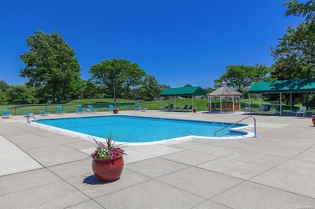 community pool featuring a yard, a patio area, fence, and a gazebo