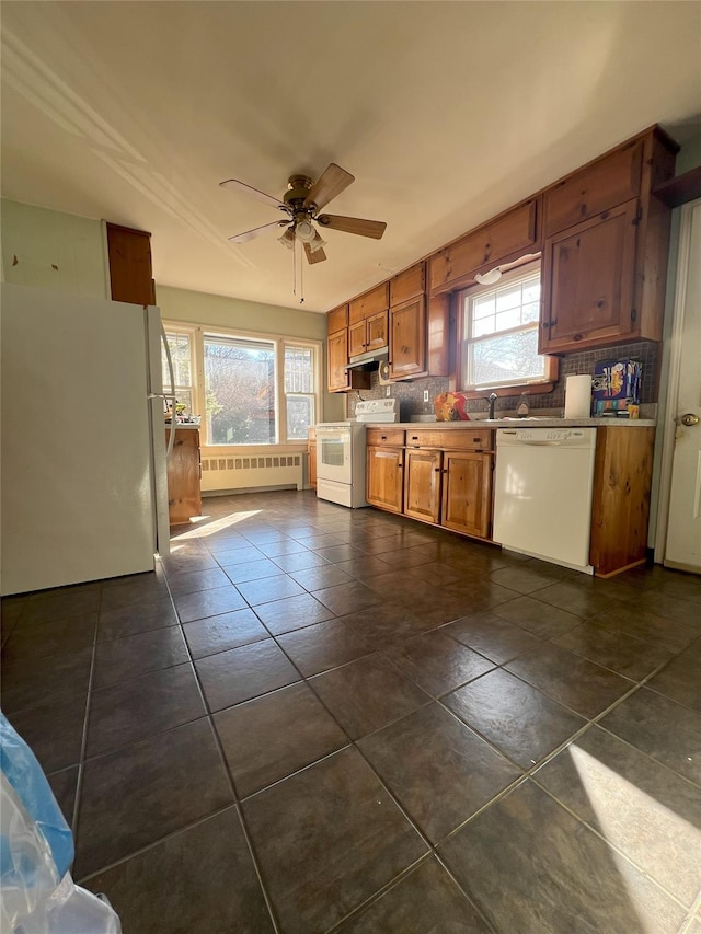 kitchen with a wealth of natural light, white appliances, radiator, and ceiling fan