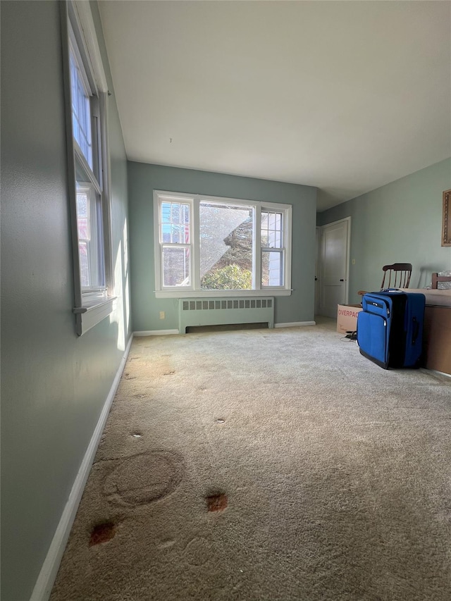 carpeted empty room with a wealth of natural light and radiator