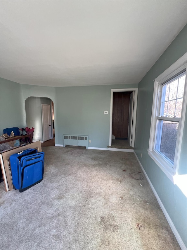 unfurnished living room with radiator and carpet