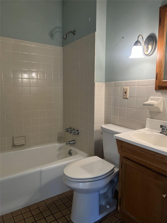 full bathroom with tile patterned floors, vanity, tile walls, toilet, and tiled shower / bath