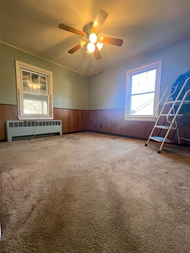 unfurnished room with carpet flooring, ceiling fan, plenty of natural light, and radiator