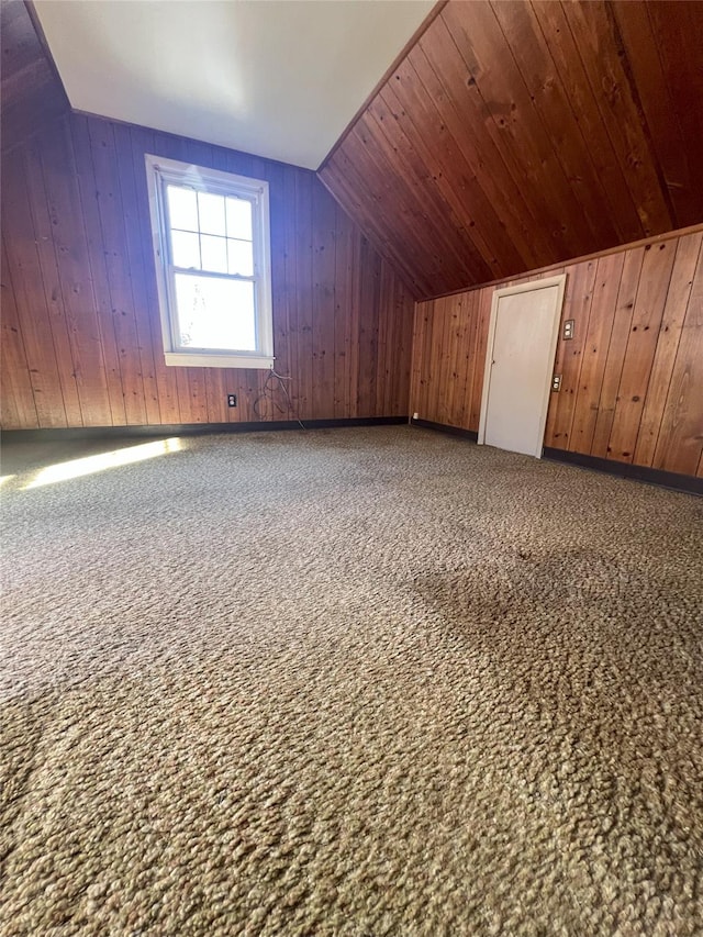 additional living space with wooden walls, lofted ceiling, and wood ceiling