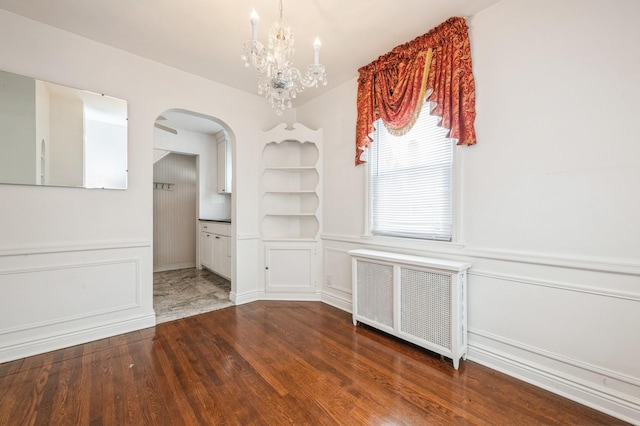 unfurnished dining area featuring an inviting chandelier, hardwood / wood-style flooring, and radiator heating unit