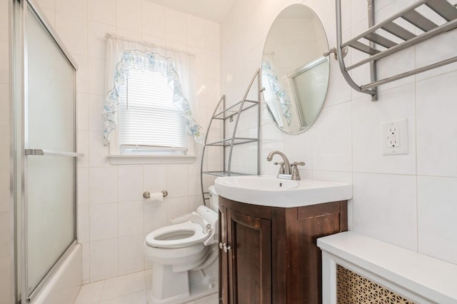 full bathroom featuring toilet, bath / shower combo with glass door, tile walls, vanity, and tile patterned flooring