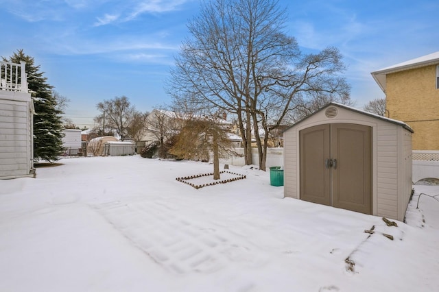 snowy yard featuring a storage unit