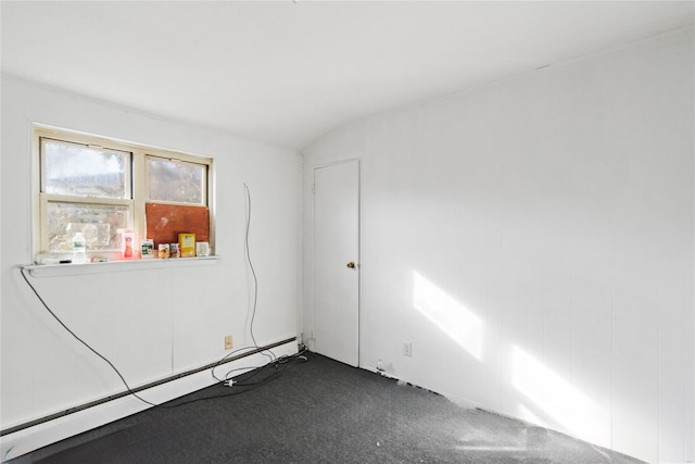 empty room featuring carpet flooring, lofted ceiling, and a baseboard heating unit