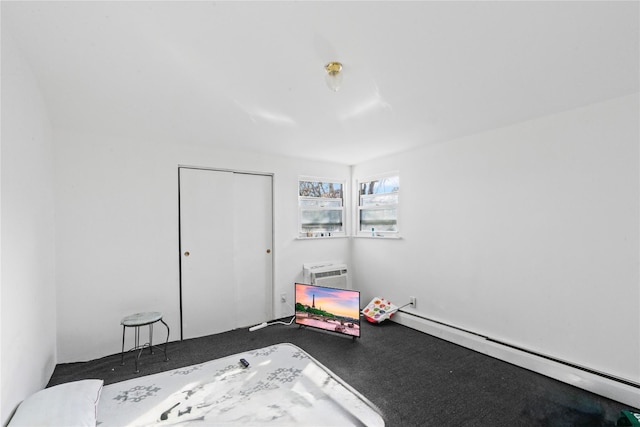 bedroom with carpet floors, a closet, a wall unit AC, and baseboard heating