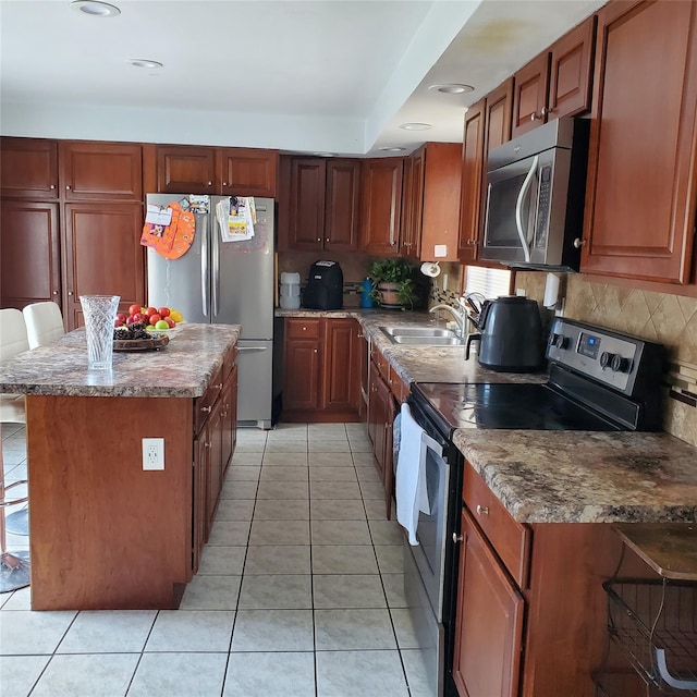 kitchen with sink, tasteful backsplash, a breakfast bar area, light tile patterned flooring, and appliances with stainless steel finishes