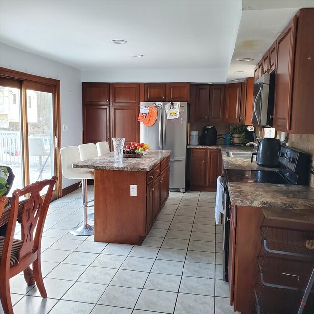 kitchen featuring a kitchen bar, appliances with stainless steel finishes, light tile patterned floors, and a kitchen island