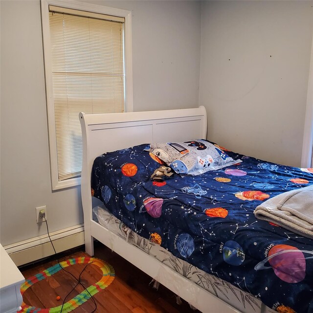 bedroom with hardwood / wood-style flooring and a baseboard heating unit