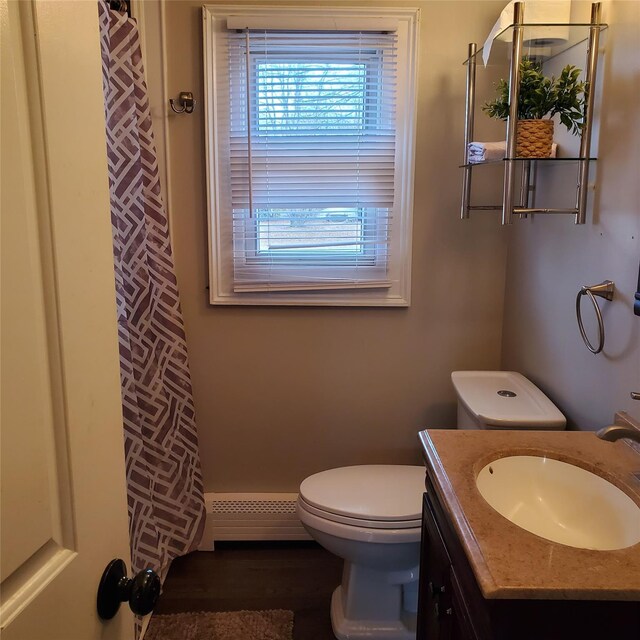 bathroom with a shower with curtain, vanity, toilet, and baseboard heating