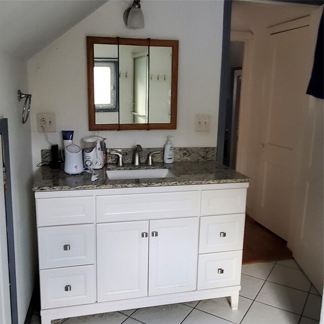 bathroom featuring tile patterned flooring, vanity, and vaulted ceiling