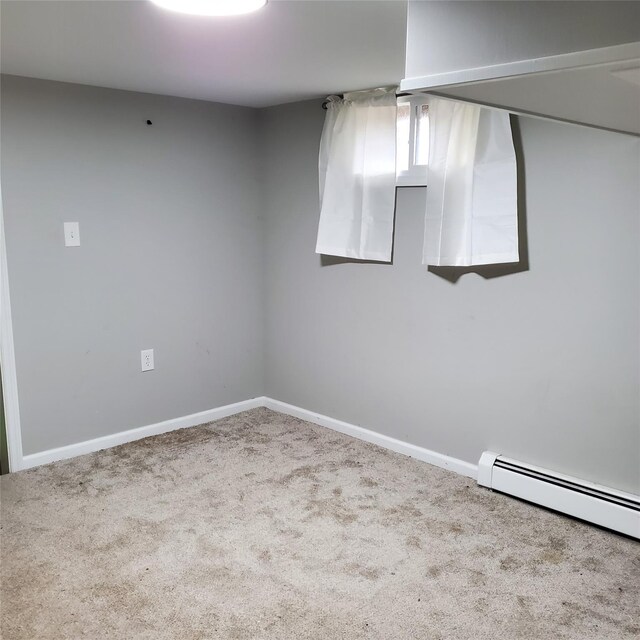 spare room featuring light carpet and a baseboard heating unit