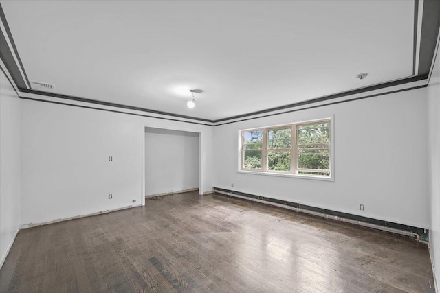 unfurnished bedroom featuring wood-type flooring, ornamental molding, and baseboard heating