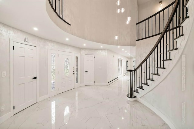 entrance foyer featuring a towering ceiling and a baseboard heating unit