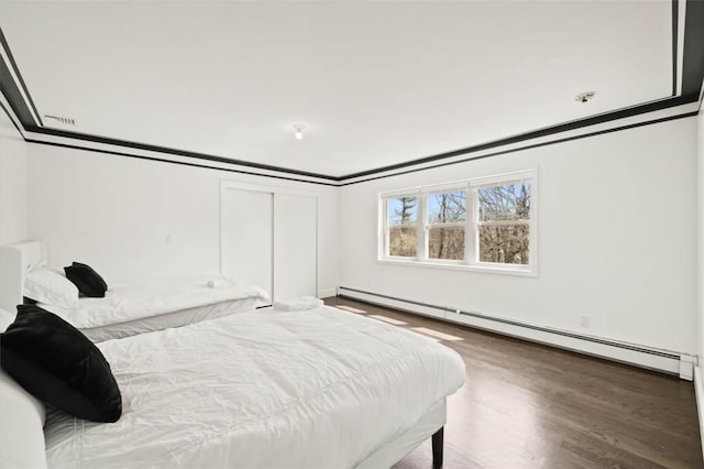 bedroom featuring hardwood / wood-style flooring, crown molding, and a baseboard heating unit