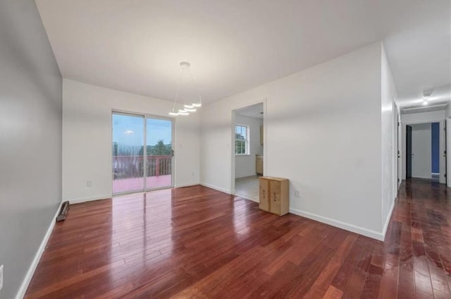 spare room with dark hardwood / wood-style flooring and a chandelier